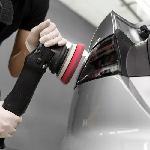 covek drzi alat u ruci i polira farove na autu