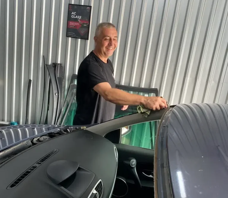 covek radi zamenu vetrobranskog stakla na automobilu